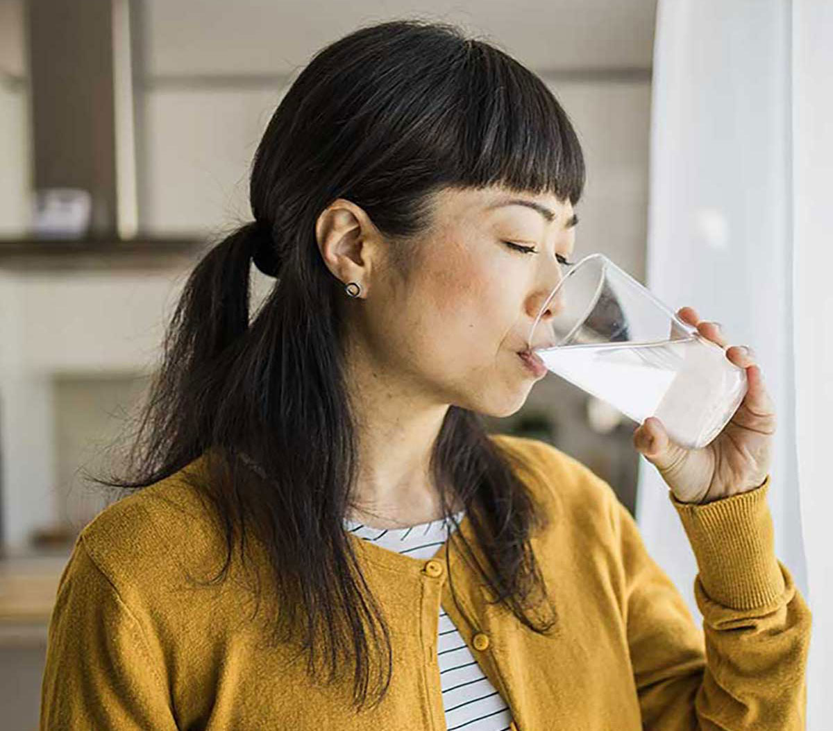 Young adult with UCD smiling while drinking OLPRUVA from a glass, highlighting its palatable taste and ease of administration. (Not actual patient).
