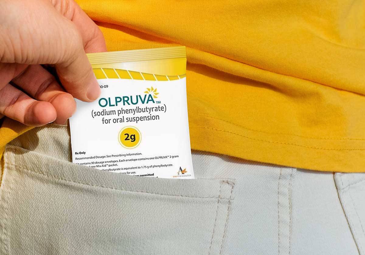 Compact, premeasured OLPRUVA packets shown in a pocket, illustrating portable convenience for the treatment of certain UCDs.